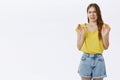 Portrait of disgusted displeased european female in yellow t-shirt and shorts raising arms in antipathy and aversion