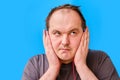 Portrait of disheveled-looking adult man listening to music with headphones, blue studio background Royalty Free Stock Photo