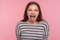 Portrait of disobedient funny woman in striped sweatshirt showing tongue out, expressing displeasure, teasing Royalty Free Stock Photo