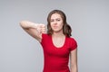 Portrait of displeased young woman showing thumb down gesture on gray background Royalty Free Stock Photo