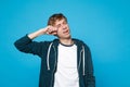 Portrait of dissatisfied disconcerted young man in casual clothes crying and wiping tears on blue wall Royalty Free Stock Photo