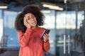 Portrait of dissatisfied sad disappointed woman inside office, businesswoman with phone in hands looking at camera Royalty Free Stock Photo