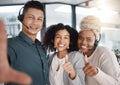 Portrait of a diverse group of happy smiling call centre telemarketing agents gesturing thumbs up while taking selfies Royalty Free Stock Photo