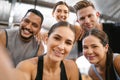 Portrait of a diverse group of happy sporty people taking selfies while exercising together in a gym. Cheerful motivated Royalty Free Stock Photo