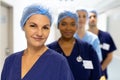 Portrait of diverse group of healthcare workers wearing surgical caps smiling in hospital corridor Royalty Free Stock Photo