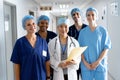 Portrait of diverse group of healthcare workers wearing surgical caps smiling in hospital corridor Royalty Free Stock Photo