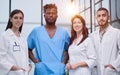 Portrait of a diverse group of male and female doctors smiling in a hospital corridor.