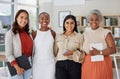 Portrait of diverse group of smiling ethnic businesswomen standing together in office, holding technology and paperwork Royalty Free Stock Photo