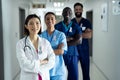 Portrait of diverse group of smiling healthcare workers wearing cancer ribbons standing in corridor Royalty Free Stock Photo