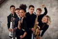 Portrait of diverse group of young people musical band playing with instruments - on gray concrete background. Royalty Free Stock Photo
