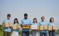 portrait diverse of people in volunteer blue t-shirt holding donation box and donated items standing in the park