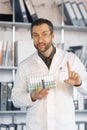 Portrait of a doctor holding a holder with test tubes and samples. He shows a gesture of attention. Royalty Free Stock Photo