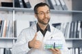 Portrait of a doctor holding a holder with test tubes and samples. He shows a thumbs up gesture. Royalty Free Stock Photo