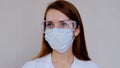 Portrait of doctor in scrubs. A female doctor in a protective cap and face mask in safety measures against the