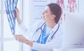 Portrait of doctor sitting in office holding xray image, working on computer