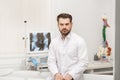 Portrait of doctor in white coat at workplace with medical staff on the background. Male doctor working at office desk Royalty Free Stock Photo