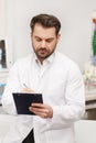 Portrait of doctor in white coat at workplace with medical staff on the background. Male doctor working at office desk Royalty Free Stock Photo