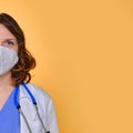 Portrait of a doctor woman in medical mask, closeup. Nurse in a blue uniform and a protective mask on a yellow background