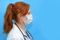 Portrait of a doctor woman in medical mask, closeup. Nurse in a white uniform and a protective mask on a blue background, profile