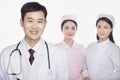 Portrait of doctor, young nurses in background, studio shot