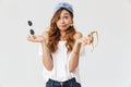 Portrait of doubtful beautiful woman 20s hesitating while holding two pairs of sunglasses, isolated over white background