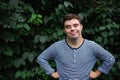 Portrait of down syndrome adult man standing outdoors at green background, looking at camera.