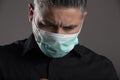 Portrait of downcast man with medical protection mask on gray studio background. Coronavirus quarantine concept