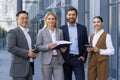 Portrait of a dream team, four business people men and women smiling and looking at the camera, colleagues outside an