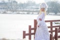 Woman Winter Fashion. Portrait of Sensual Caucasian Blond in Knitted White Dress and Kerchief with Fur Kokoshnik.Posing on Bridge Royalty Free Stock Photo