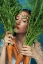 Portrait of dreaming female fashion model hiding behind carrot leaves