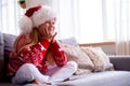 Portrait dreaming girl with closed eyes in Santa hat and Christmas costume sitting at home . New Year Holidays concept
