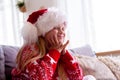 Portrait dreaming girl with closed eyes in Santa hat and Christmas costume sitting at home . New Year Holidays concept