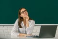 Portrait of dreaming young college student in classroom on blackboard background, copy space. Royalty Free Stock Photo