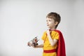 Portrait Dreamy boy in a red cape plays with a toy airplane