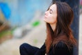 Portrait of a dreamy cute happy woman worker meditating outdoors with big eyes closed, sitting with the effect of blur closeup. De