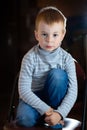 Portrait of dreamy pensive blond boy with gaze his eyes over dark background with specks of dust flying in backlight with flares Royalty Free Stock Photo