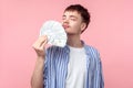 Portrait of dreamy rich brown-haired man smelling money. indoor studio shot isolated on pink background