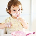 Portrait of eating baby girl with dirty face in high chair Royalty Free Stock Photo