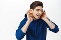 Portrait of eavesdropping guy bending closer and holding hands near ear, cant hear you, overhear smth interesting Royalty Free Stock Photo