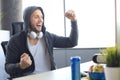 Portrait of ecstatic gamer guy in headphones screaming and rejoicing while playing video games on computer