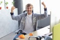 Portrait of ecstatic gamer guy in headphones screaming and rejoicing while playing video games on computer