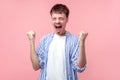 Portrait of ecstatic winner, successful brown-haired man screaming for joy. isolated on pink background