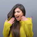 Portrait of a ecstatic woman with spread hands against gray background