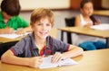 Portrait, education and learning with a student boy sitting by his desk in a classroom for child development. School Royalty Free Stock Photo