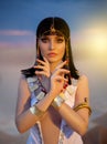 Portrait of Egypt Style woman. Sexy girl goddess Queen Cleopatra stand in desert pyramids. Art ancient pharaoh costume