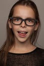 Portrait of an eight-year-old girl with a calm mood, in a black blouse and glasses with black rim. Studio photo session