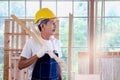 Portrait of elderly Asian carpenter with mustache wearing antiknock helmet and cloth gloves, holding wooden plank, senior Royalty Free Stock Photo