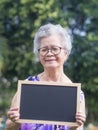 Portrait of an elderly Asian woman with short gray hair holding a mini blackboard, smiling and looking at the camera Royalty Free Stock Photo