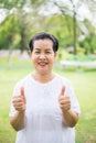 Portrait of a elderly asian woman standing and showing thumb up at outdoor,Happy and smiling,Freedom time Royalty Free Stock Photo