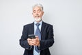 Portrait of elderly businessman in suit holding mobile phone in hand with happy smiling face. Person with smartphone Royalty Free Stock Photo